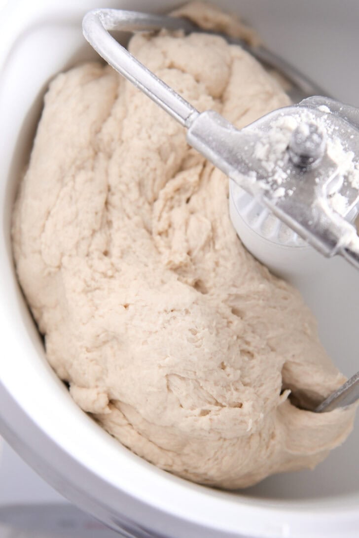Sourdough bagel dough in white Bosch bowl fitted with the dough hook.