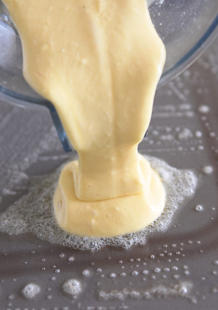 Pouring cottage cheese pancake batter on buttered griddle.