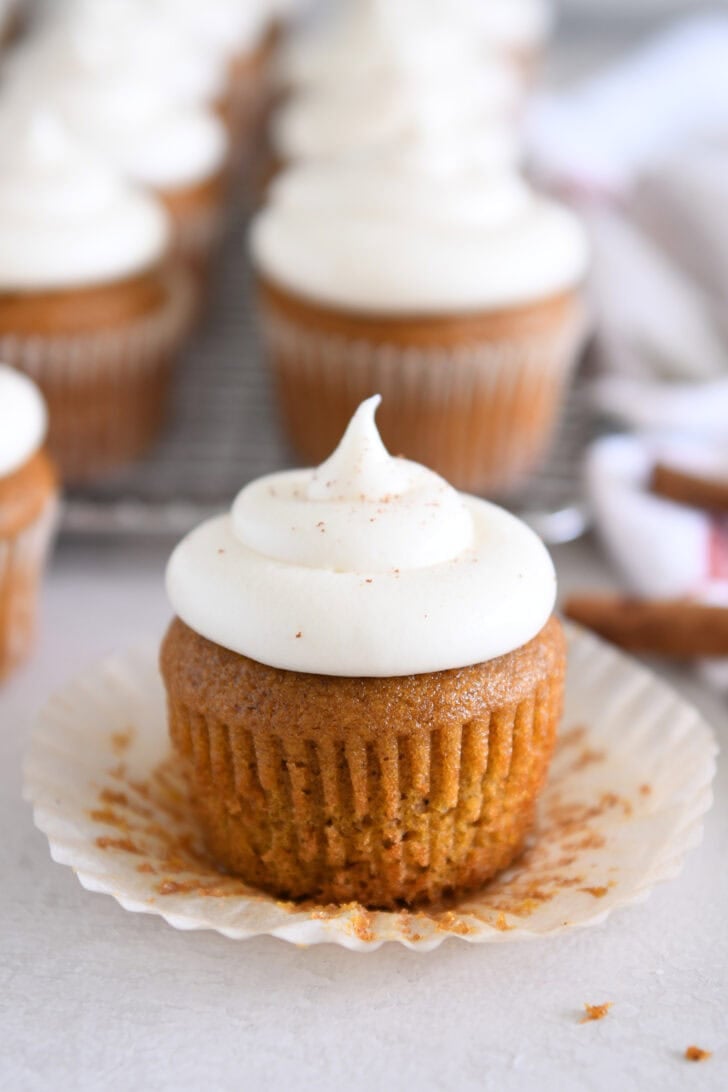 Unwrapped pumpkin cupcake topped with whipped cream cheese frosting.
