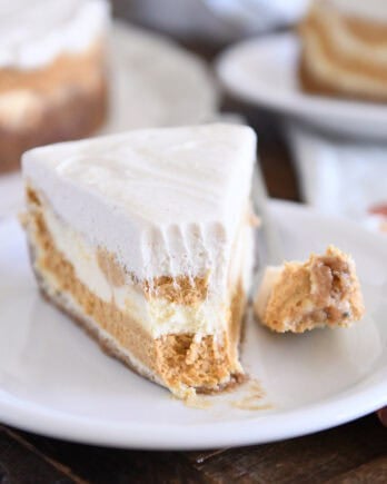 Slice of pumpkin swirl cheesecake with bite removed on white plate.