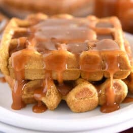 Two squares of pumpkin waffles on white plate smothered in buttermilk caramel syrup.