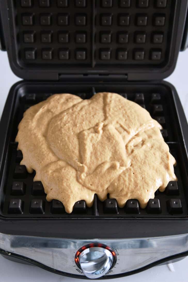 Pumpkin waffle batter spread in square waffle iron.