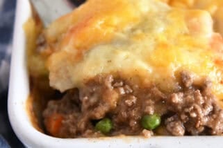 A spatula taking a helping of shepherd's pie out of a white casserole dish.