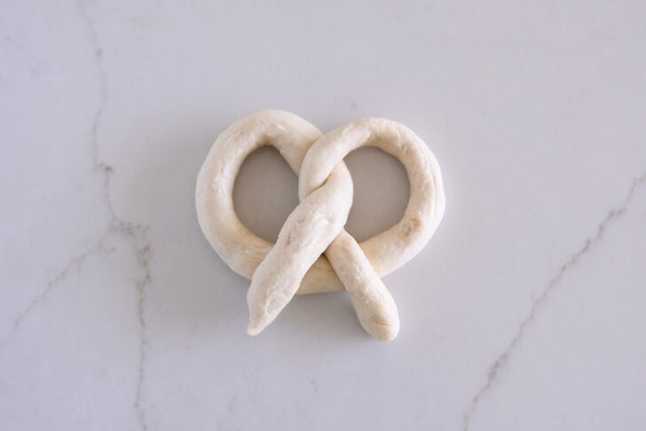 Shaped piece of dough into soft pretzel shape before baking.
