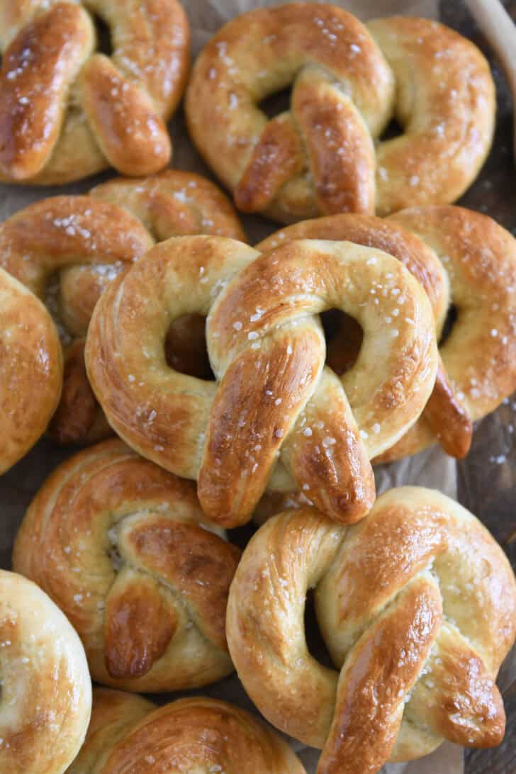 Stack of several homemade soft pretzels sprinkled with salt.