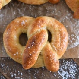 Top down view of baked and buttered soft homemade pretzel sprinkled with coarse salt.