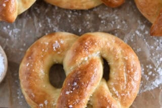 Top down view of baked and buttered soft homemade pretzel sprinkled with coarse salt.