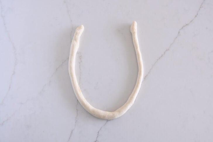 Piece of long thin pretzel dough formed into horseshoe shape.