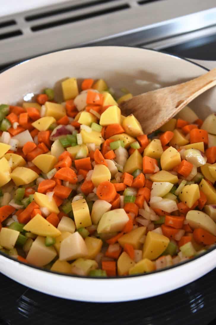 Cast iron pan filled with carrots, potatoes, celery, or onions.
