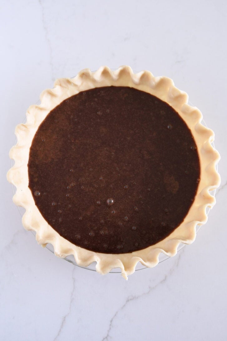 Top down view of unbaked pie shell in 9-inch pie plate filled with chocolate custard mixture.