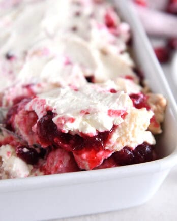 Scoop of cranberry orange angel food cake dessert in white baking pan.