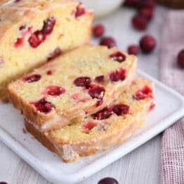 Two slices cut from cranberry orange loaf on white tray.