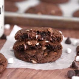 Two half chocolate cookies with gooey melted chocolate chips and mini marshmallows stacked on one full cookie.