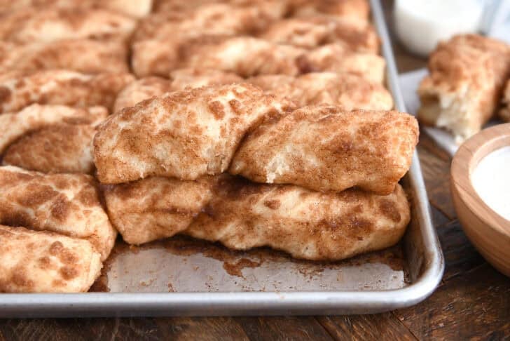 Baked pan of cinnamon sugar twists with one piece stacked on top of another.