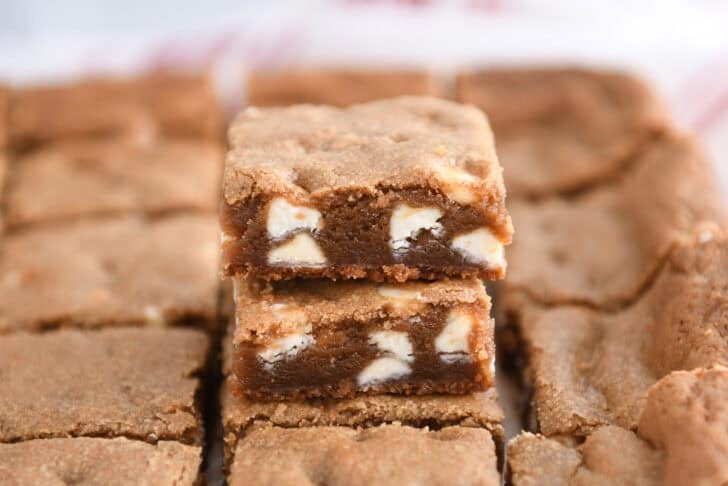 Two squares of gingerbread white chocolate blondie bars stacked.