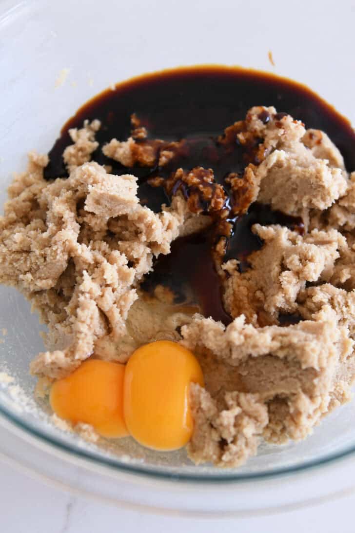 Glass bowl with butter and brown sugar batter, eggs, and molasses.