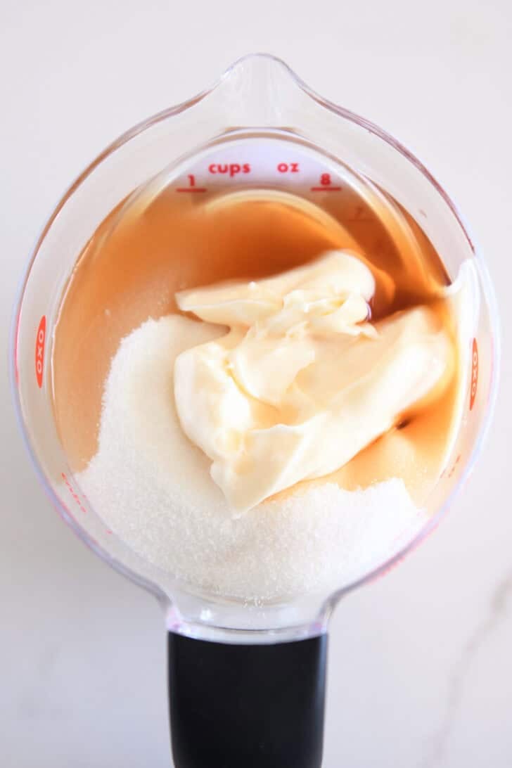 Top down view of a liquid measuring cup with sugar, mayonnaise, and balsamic vinegar.