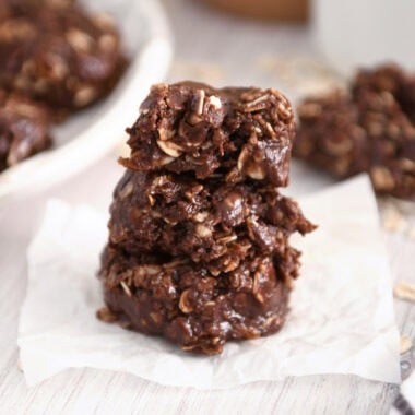 Three chocolate no-bake cookies stacked on parchment.