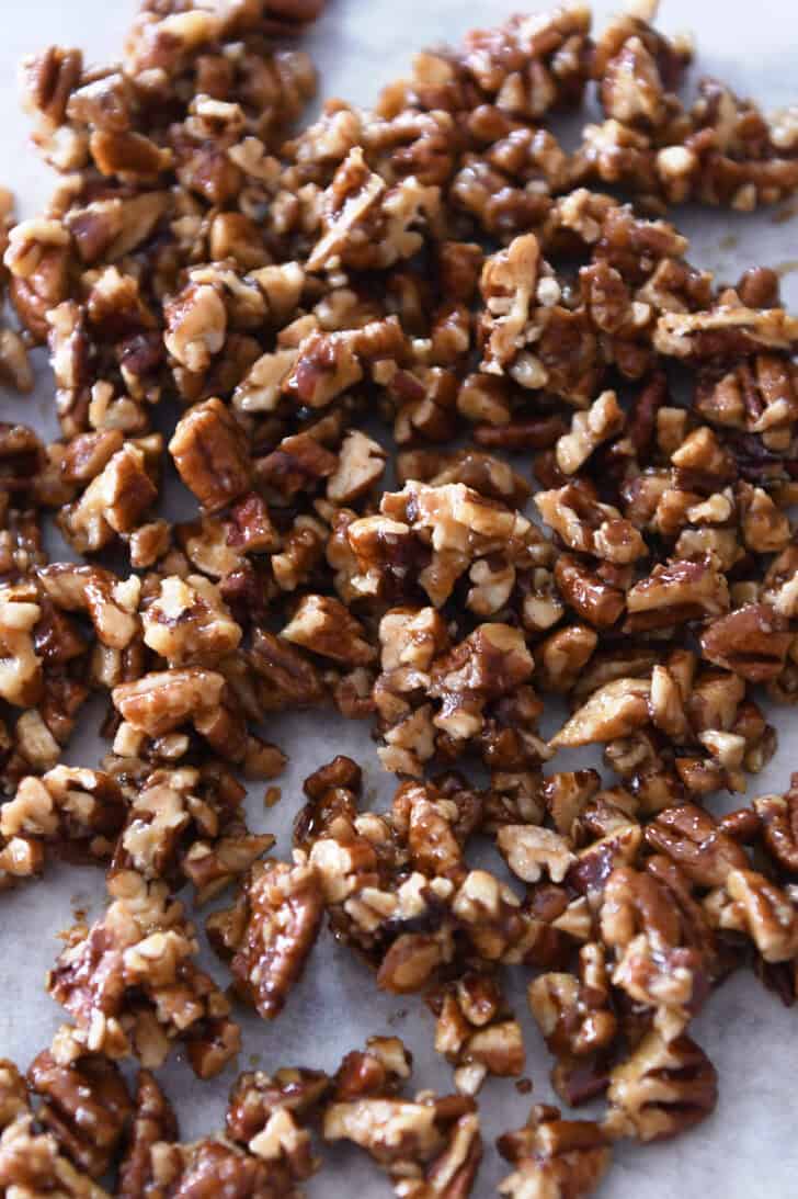 Top down view of pieces of candied pecans on a sheet of parchment.