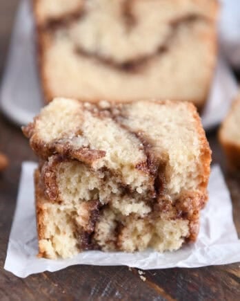 Two half slices of cinnamon swirl quick bread stacked on white parchment paper.