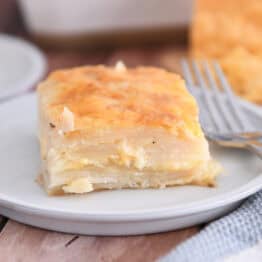 Square of baked au gratin potatoes on gray plate.
