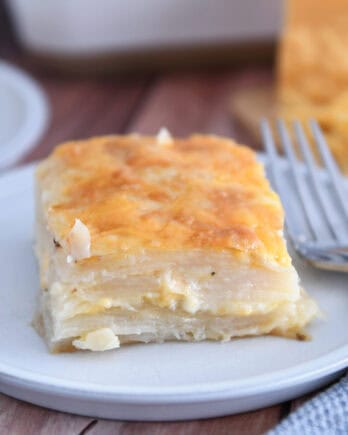Square of baked au gratin potatoes on gray plate.