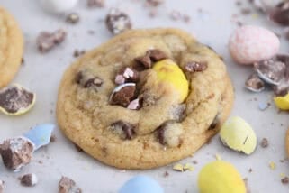 Baked cookies on parchment paper with crushed and whole cadbury eggs scattered around.