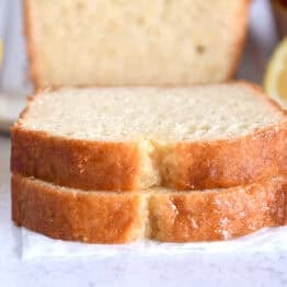 Two slices of lemon quick bread stacked on parchment paper.