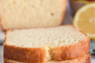 Two slices of lemon quick bread stacked on parchment paper.