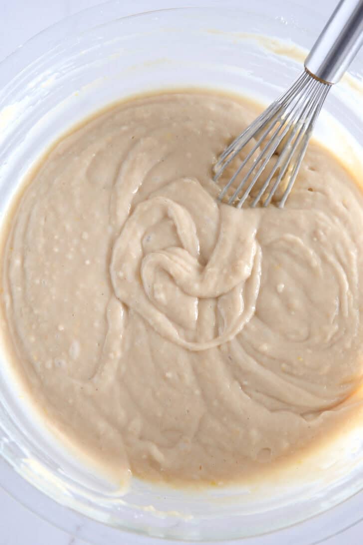 Glass bowl with lemon quick bead batter and whisk.