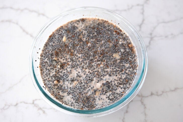 Glass bowl with basil seeds, oats, and almond milk.