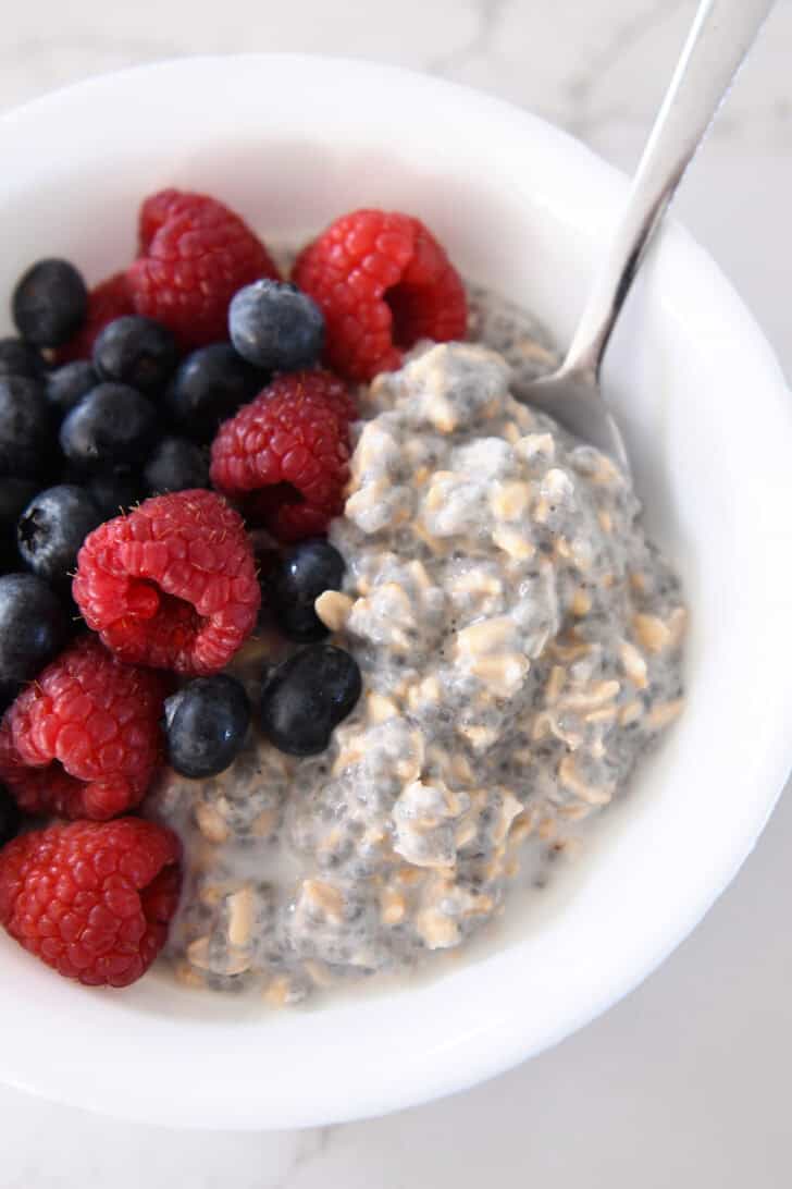 White bowl with chia oats, blueberries, and raspberries.