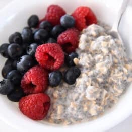 White bowl with chia oats, blueberries, and raspberries.