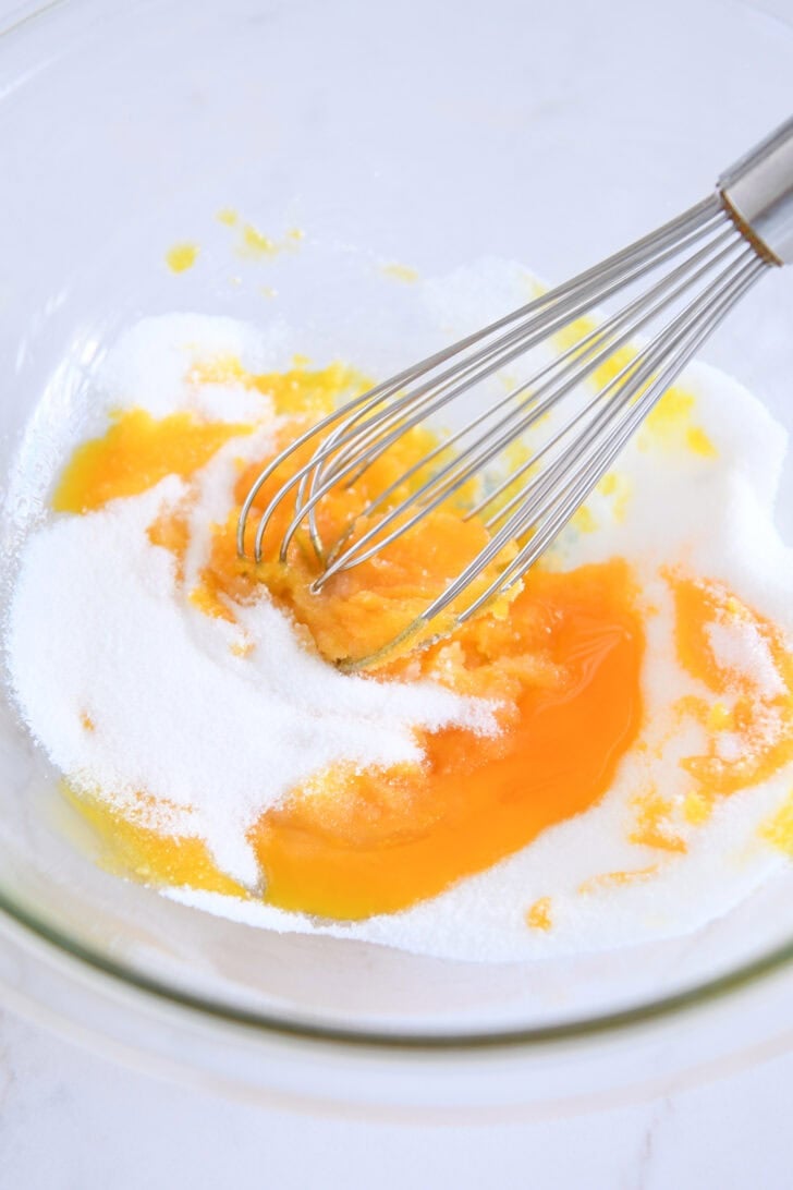Glass bowl with egg yolks and granulated sugar.