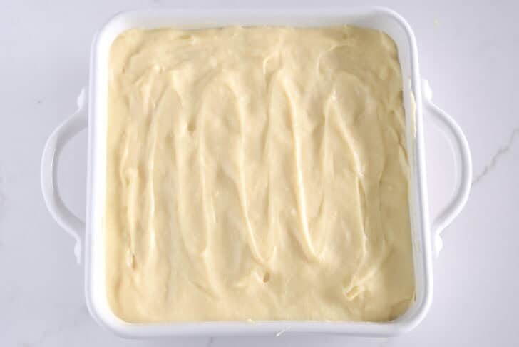 White square 8X8 baking dish with vanilla pudding on top of bananas and nilla wafers.