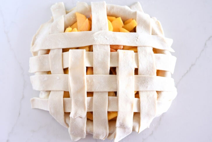 Assembling lattice pie crust on fresh peach pie.