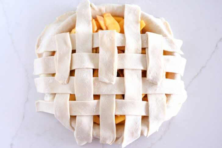 Assembling lattice pie crust on fresh peach pie.