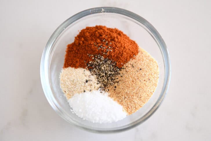 Glass bowl with smoked paprika, onion powder, garlic powder, salt and pepper.