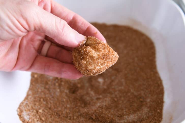Dipping buttery dough in cinnamon and sugar.