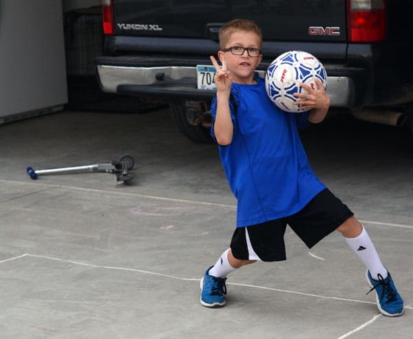 A little boy holding a soccer ball and playing outside. 