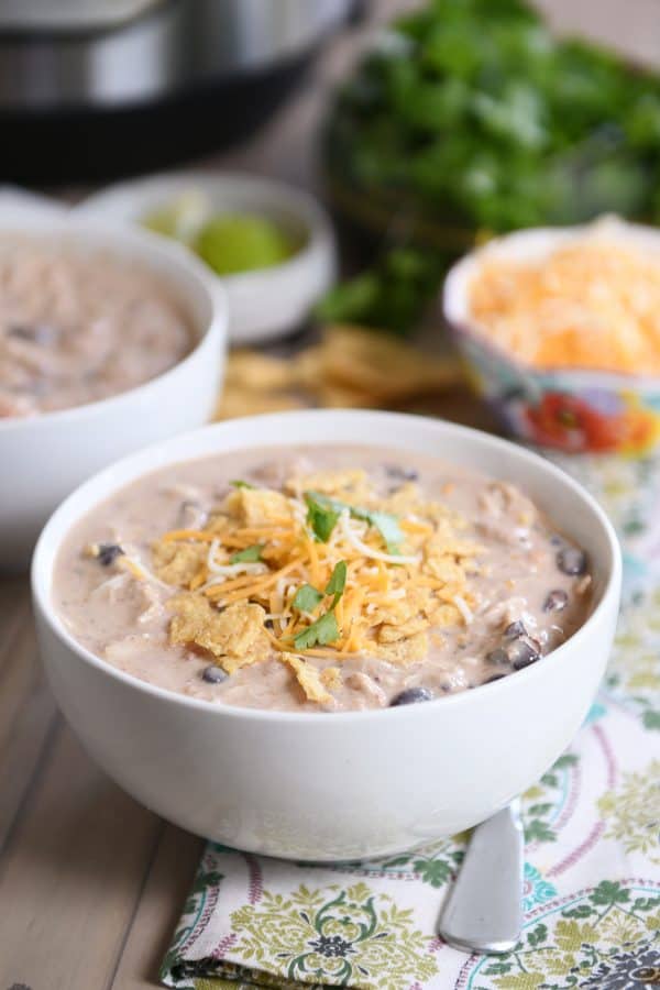 Instant Pot white chicken chili in white bowl and shredded cheese.