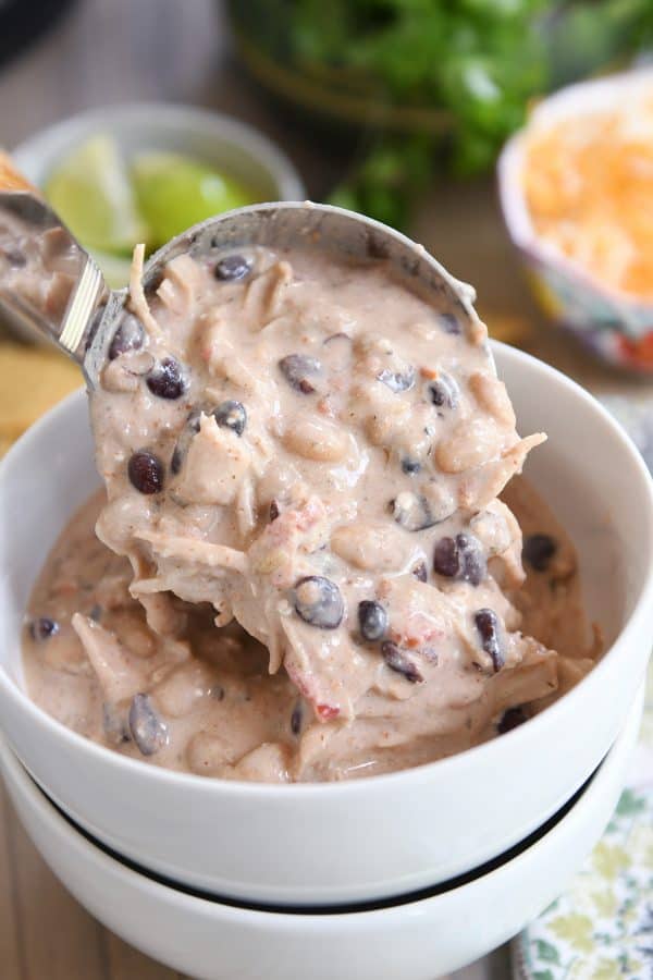 Ladling in Instant Pot white chicken chili into white bowl.
