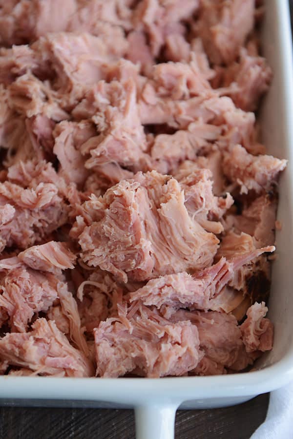 A white dish full of shredded, baked ham. 