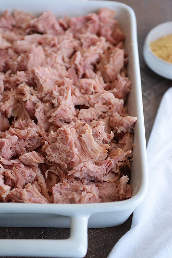 A white dish full of shredded baked ham. 