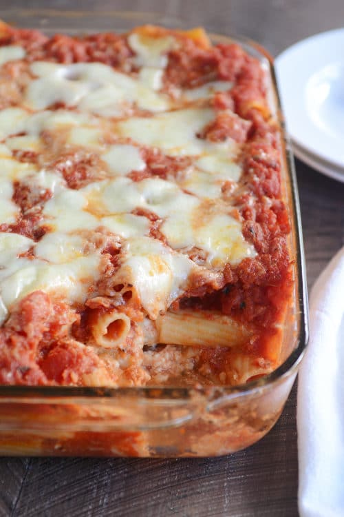 Baked ziti in a glass dish with a spoonful taken out.