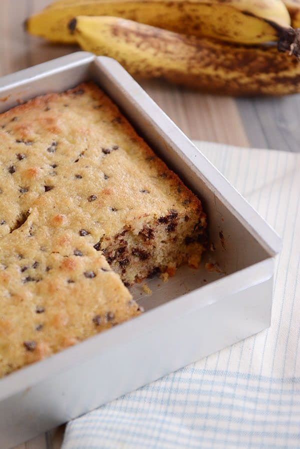 A metal pan of banana chocolate chip snack cake with one piece taken out.