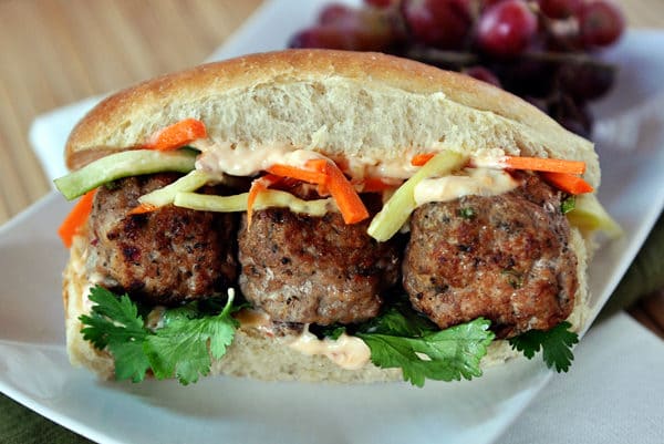 A meatball banh mi sub sandwich on a white plate.