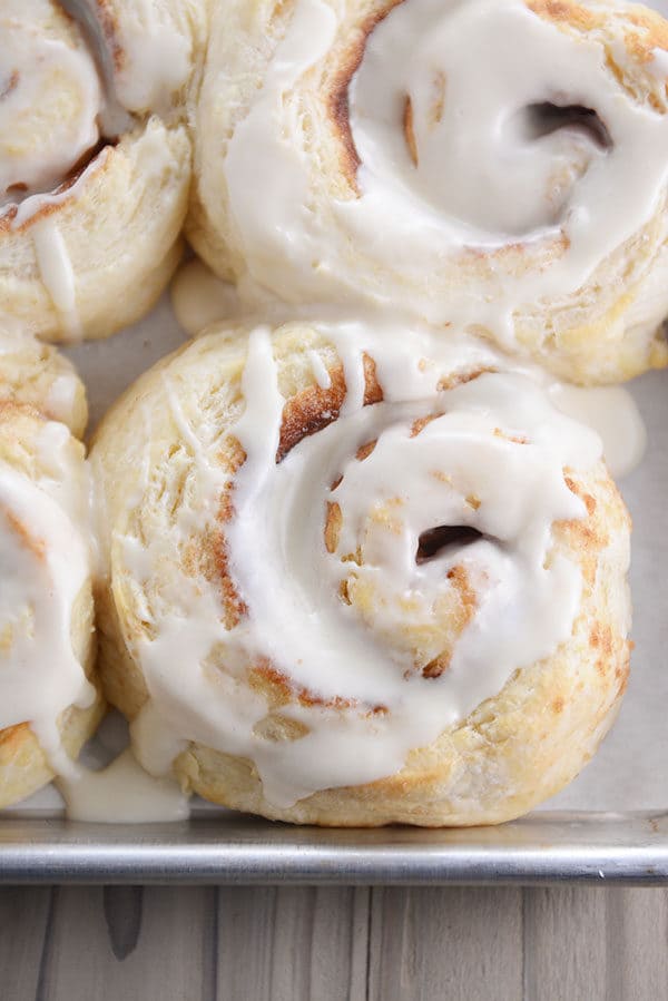 Top view of a frosting-topped biscuit cinnamon rolls on a cookie sheet.