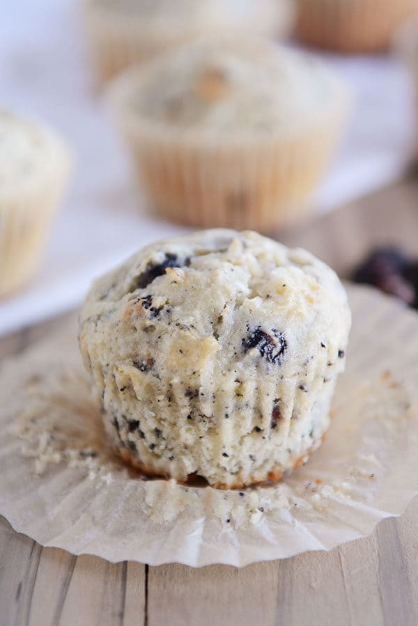 An unwrapped blueberry muffin sitting on the liner. 