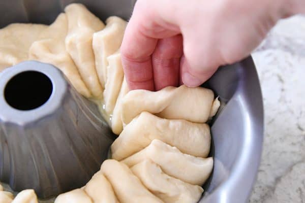 Layering squares of dough in bundt pan.